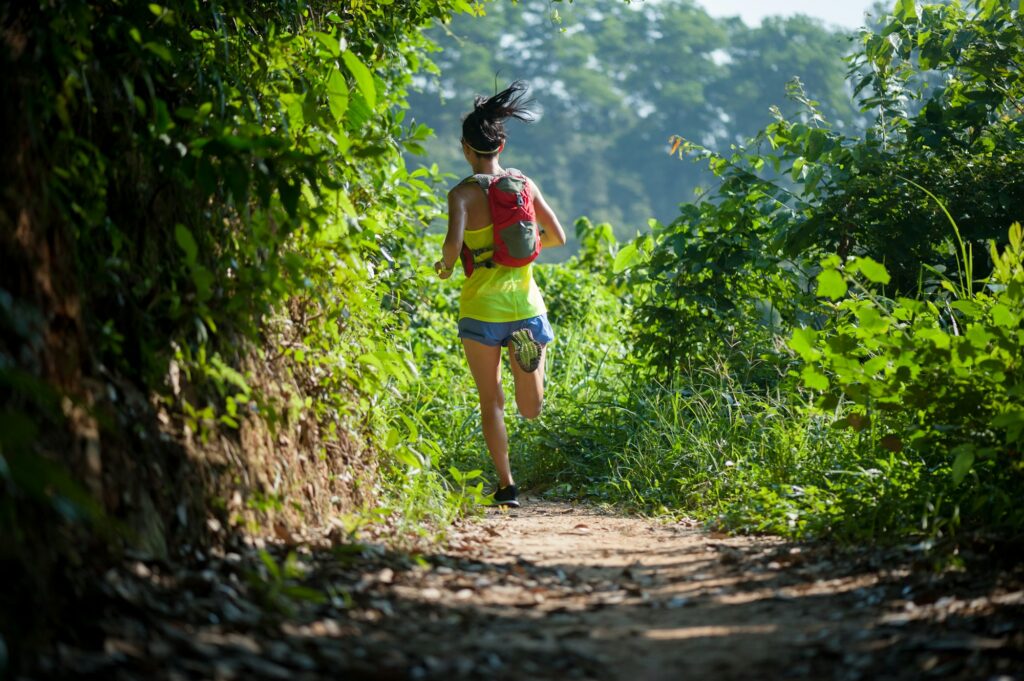 Young woman trail runner running in sunrise tropical forest